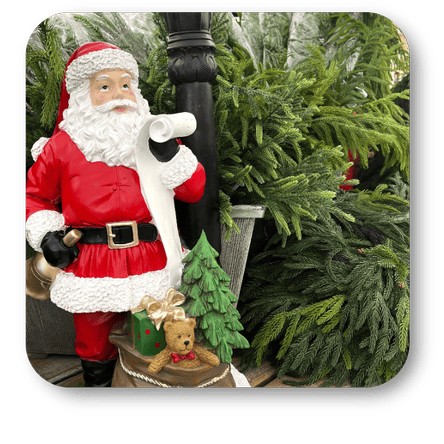 Decorative figure of Santa Claus with a teddy bear and small tree, standing next to a Christmas tree at Dewayne's in Selma, NC minutes from Raleigh, Cary, Clayton, Garner, Smithfield, Goldsboro