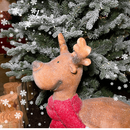 Decorative reindeer with a red scarf in front of a Christmas tree with snowflakes at Dewayne's In Selma, NC