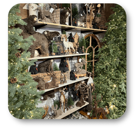 Decorative shelves with rustic animal figurines against a Christmas tree backdrop in the country Christmas room of Christmas Land 2025 at Dewayne's in Selma, NC minutes from Raleigh, Cary, Clayton, Garner, Smithfield, Goldsboro