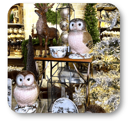 Decorative owls and deer figurines on a table with a Christmas tree in the background in the country Christmas room of Christmas Land 2025 at Dewayne's in Selma, NC minutes from Raleigh, Cary, Clayton, Garner, Smithfield, Goldsboro
