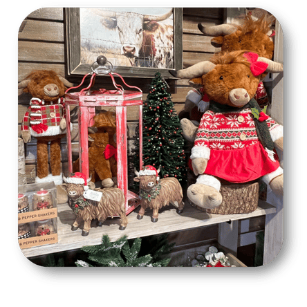 Display of stuffed highland cows in festive attire with a Christmas tree and lantern in the country Christmas room of Christmas Land 2025 at Dewayne's in Selma, NC minutes from Raleigh, Cary, Clayton, Garner, Smithfield, Goldsboro