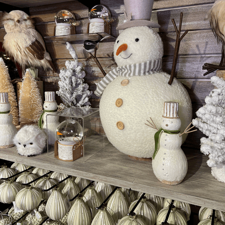 Decorative shelf with snowmen, owls, and other winter-themed ornaments against a wooden wall in the country christmas room at Dewayne's in Selma, NC