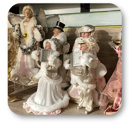 Decorative figurines of angels in vintage attire with books on a wooden surface in the gold and glamour room in christmas land 2025 at Dewayne's in Selma, NC minutes from Raleigh, Cary, Clayton, Garner, Smithfield, Goldsboro