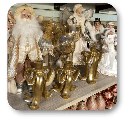 Decorative golden figurines including a Santa Claus-like character and angelic figures on a shelf in the gold and glamour room in christmas land 2025 at Dewayne's in Selma, NC minutes from Raleigh, Cary, Clayton, Garner, Smithfield, Goldsboro