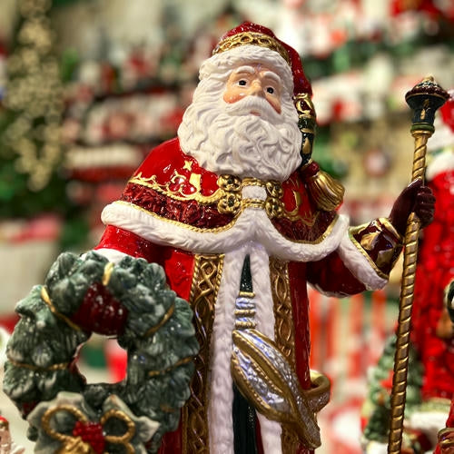 Decorative ceramic Fitz & Floyd Santa in a red and gold outfit with a wreath, against a festive background.