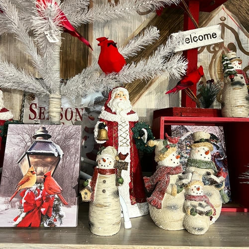 Decorative Christmas decor with Santa, snowmen, and cardinal birds on a shelf in the country Christmas room of Christmas Land 2025 at Dewayne's