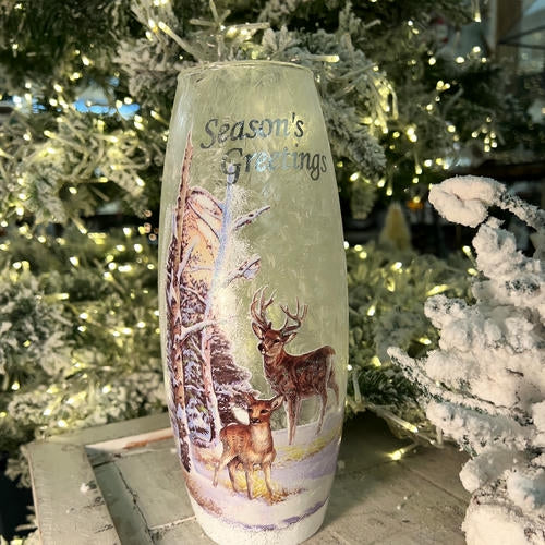 Decorative vase with deer design and 'Season's Greetings' text in front of a Christmas tree in the country Christmas room of Christmas Land 2025 at Dewayne's