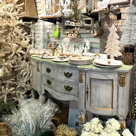 Decorative cabinet with Christmas-themed ornaments and a tree in the Moments in Thyme room at Dewayne's in Selma, NC