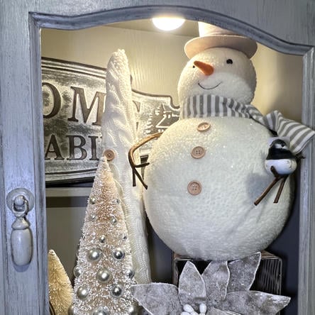 Decorative snowman with a hat and scarf, standing next to a Christmas tree and sign  in the country christmas room at Dewayne's in Selma, NC