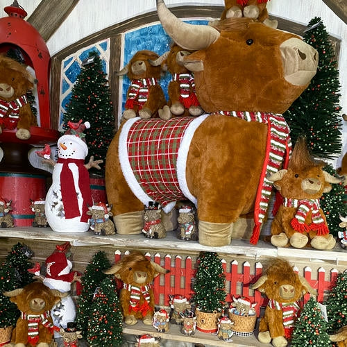 Decorative shelf with stuffed highland cows, Christmas trees, and ornaments in a festive setting in the country Christmas room of Christmas Land 2025 at Dewayne's