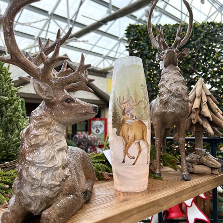 Decorative deer statues with a cylindrical light fixture featuring a deer illustration on a wooden surface at Dewayne's in Selma, NC minutes from Raleigh, Cary, Clayton, Garner, Smithfield, Goldsboro