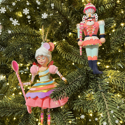 Two decorative Christmas ornaments by glitterville on a tree with lights and snowflake decorations in Kringle's kitchen in christmas land 2025 at dewayne's
