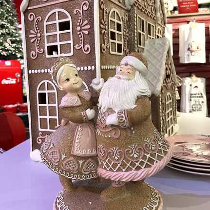 Decorative figurine of a gingerbread man and woman of Mr & Mrs Clause in front of a gingerbread house in Kringle's kitchen in christmas land 2025 at dewayne's