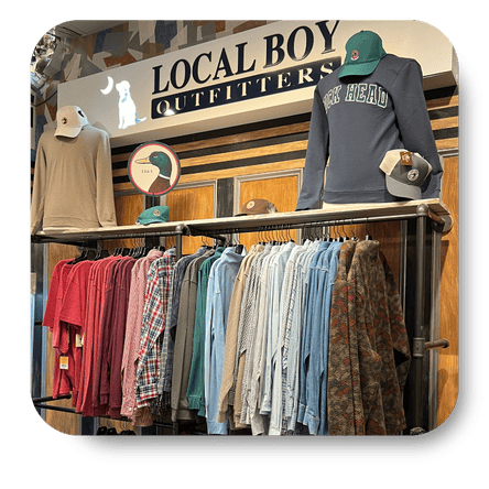 Clothing store with racks of clothes and a 'Local Boy Outfitters' sign in the men's shoppe at Dewayne's in Selma, NC minutes from Raleigh, Cary, Clayton, Garner, Smithfield, Goldsboro