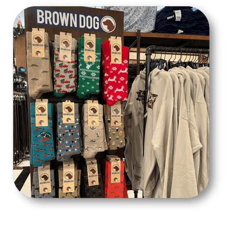 Display of socks with 'Brown Dog' branding next to hanging shirts in the men's shoppe at Dewayne's in Selma, NC minutes from Raleigh, Cary, Clayton, Garner, Smithfield, Goldsboro