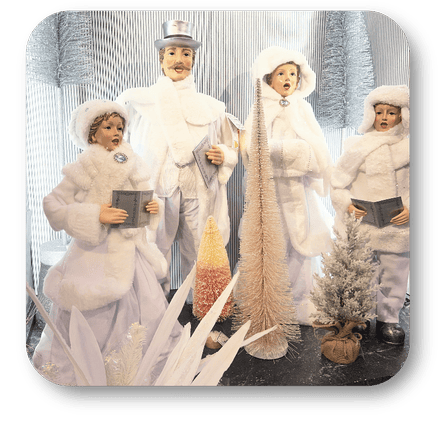 Decorative caroler figurines in winter attire with fur hats and coats against a white background in winter wonderland in Christmas Land at Dewayne's in Selma, NC minutes from Raleigh, Cary, Clayton, Garner, Smithfield, Goldsboro