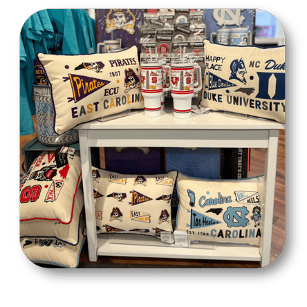 Collection of college-themed pillows with various university logos and designs at Dewayne's in Selma, NC minutes from Raleigh, Cary, Clayton, Garner, Smithfield, Goldsboro