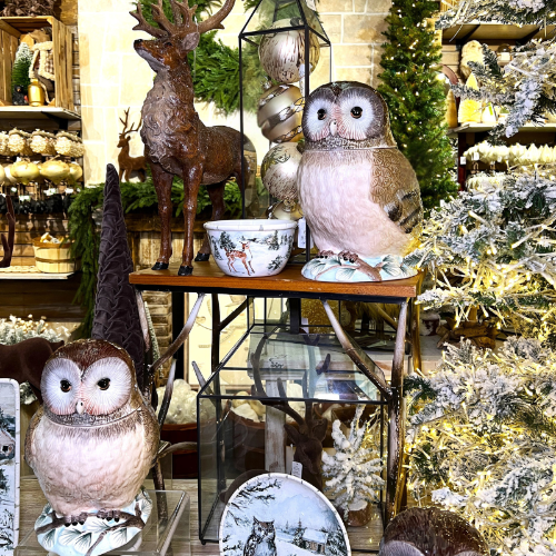 Decorative owls and deer figurines on a table with Christmas decorations in the background in the country christmas room in christmas land 2025 at Dewayne's.