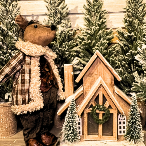 Decorative scene with a moose figure and wooden cabin in a snowy setting in the country Christmas room of Christmas Land 2025 at Dewayne's