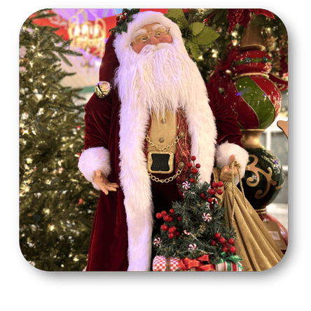 Decorative Santa Claus figure with a Christmas tree and gifts in front of a decorated Christmas tree in the grand entrance room of christmas land  at Dewayne's in Selma, NC minutes from Raleigh, Cary, Clayton, Garner, Smithfield, Goldsboro