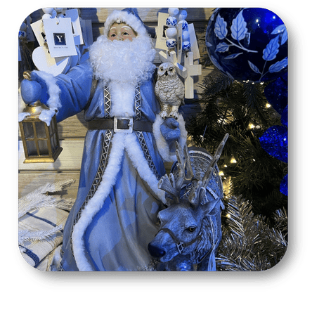 Decorative figure of a blue-clad Santa Claus with a reindeer and owl, surrounded by Christmas decorations in Christmas Land at Dewayne's in Selma, NC minutes from Raleigh, Cary, Clayton, Garner, Smithfield, Goldsboro
