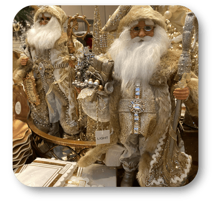 Decorative gold santa figurines with intricate details and sparkling elements on a clear background in the gold and glamour room in christmas land at Dewayne's in Selma, NC minutes from Raleigh, Cary, Clayton, Garner, Smithfield, Goldsboro