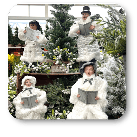 Decorative caroler figures  in white snow-like costumes with hats and books, standing in front of a Christmas tree at Dewayne's in Selma, NC minutes from Raleigh, Cary, Clayton, Garner, Smithfield, Goldsboro