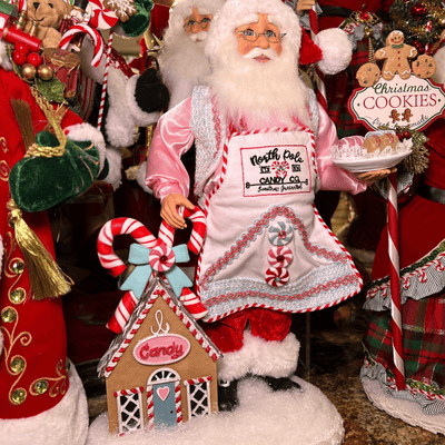 Santa Claus figure holding cookies figurines by Karen Didion in the timeless treasures room in christmas land 2025 at Dewayne's