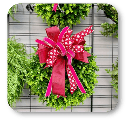 Green wreath with a pink polka dot Happy bow. One of many variety of colorful bows to add the finishing touch in the greenhouse atrium at Dewayne's in Selma, NC minutes from Raleigh, Cary, Clayton, Garner, Smithfield, Goldsboro