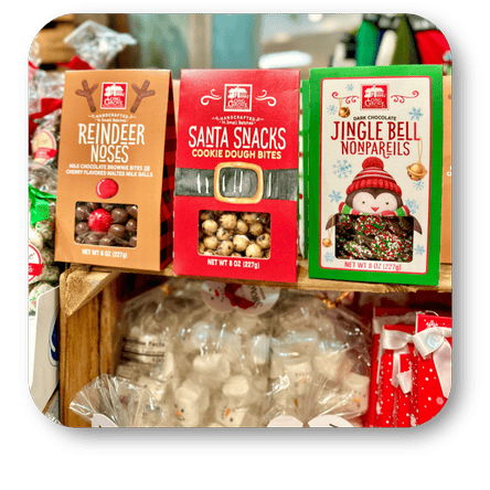 Three festive snack packages of holiday candy on a wooden surface with blurred background in the sweet shop at Dewayne's in Selma, NC minutes from Raleigh, Cary, Clayton, Garner, Smithfield, Goldsboro