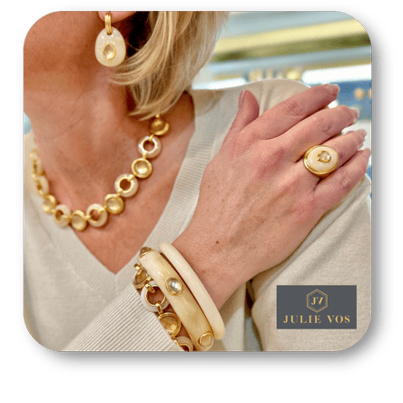 Woman wearing Julie Vos gold jewelry including necklace, bracelet, and ring with a blurred background in the boutique