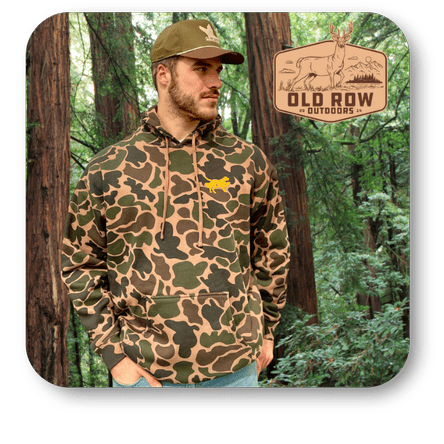 Man wearing a camouflage hoodie and cap in a forest setting with Old Row Outdoors logo in the men's shoppe at Dewayne's in Selma, NC minutes from Raleigh, Cary, Clayton, Garner, Smithfield, Goldsboro