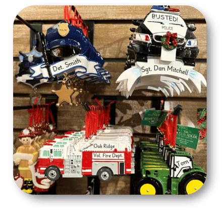 Collection of ornaments including police officers, a fire truck, and a tractor on a wooden surface in the personalization room at Dewayne's in Selma, NC minutes from Raleigh, Cary, Clayton, Garner, Smithfield, Goldsboro