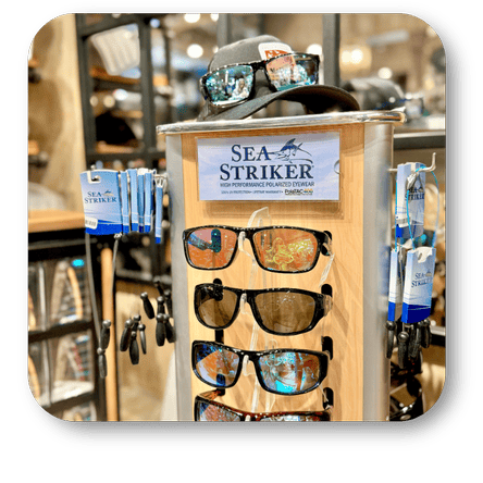 Display of Sea Striker sunglasses with a cap on top in the men's shoppe at Dewayne's in Selma, NC minutes from Raleigh, Cary, Clayton, Garner, Smithfield, Goldsboro
