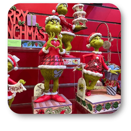Decorative Grinch figurines by Jim Shore with Christmas-themed decorations on a red background  in santa's workshop at Dewayne's in Selma, NC minutes from Raleigh, Cary, Clayton, Garner, Smithfield, Goldsboro
