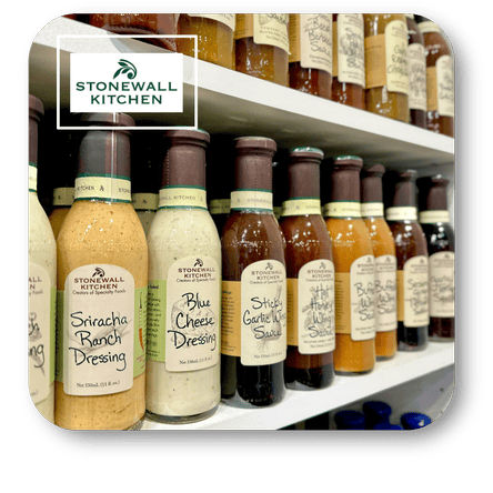Shelf with Stonewall Kitchen dressings and sauces, featuring a mix of bottles on a white background at Dewayne's in Selma, NC minutes from Raleigh, Cary, Clayton, Garner, Smithfield, Goldsboro