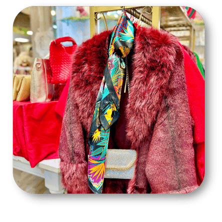 Red fur coat with a colorful scarf draped over a chair in the boutique at Dewayne's in Selma, NC minutes from Raleigh, Cary, Clayton, Garner, Smithfield, Goldsboro
