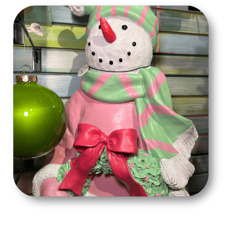 Decorative snowman figure with a pink dress and green hat in the Kringle's Kitchen room in christmas land at Dewayne's in Selma, NC minutes from Raleigh, Cary, Clayton, Garner, Smithfield, Goldsboro