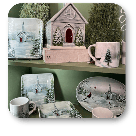 Collection of decorative items including mugs, plates, and a small house with winter scene in the moments of thyme room in christmas land at Dewayne's in Selma, NC minutes from Raleigh, Cary, Clayton, Garner, Smithfield, Goldsboro