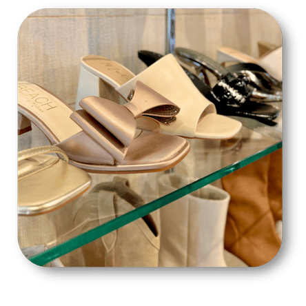 Gold high-heeled dress shoes on a glass surface with a blurred background in the boutique at Dewayne's in Selma, NC minutes from Raleigh, Cary, Clayton, Garner, Smithfield, Goldsboro